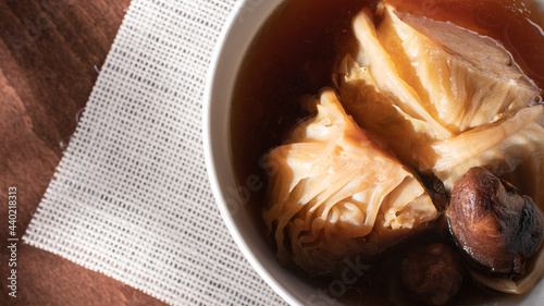 The traditional food of Asia, Boiled cabbage and shiitake soup with the soy sauce in the white bowl with dried shiitake and all place on the wooden table in closed up view