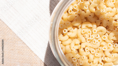 The opened macaroni's bottle with the natural light place on the burlap hessian with the copy space on the left side