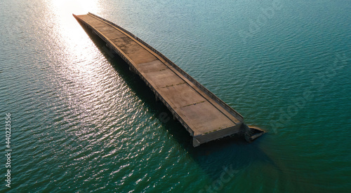 aerial view of old sink bridge pop out from water surface in Pasak dam with sunset light reflection in Lopburi, Thailand, unseen travel destination, drone high angle top view
