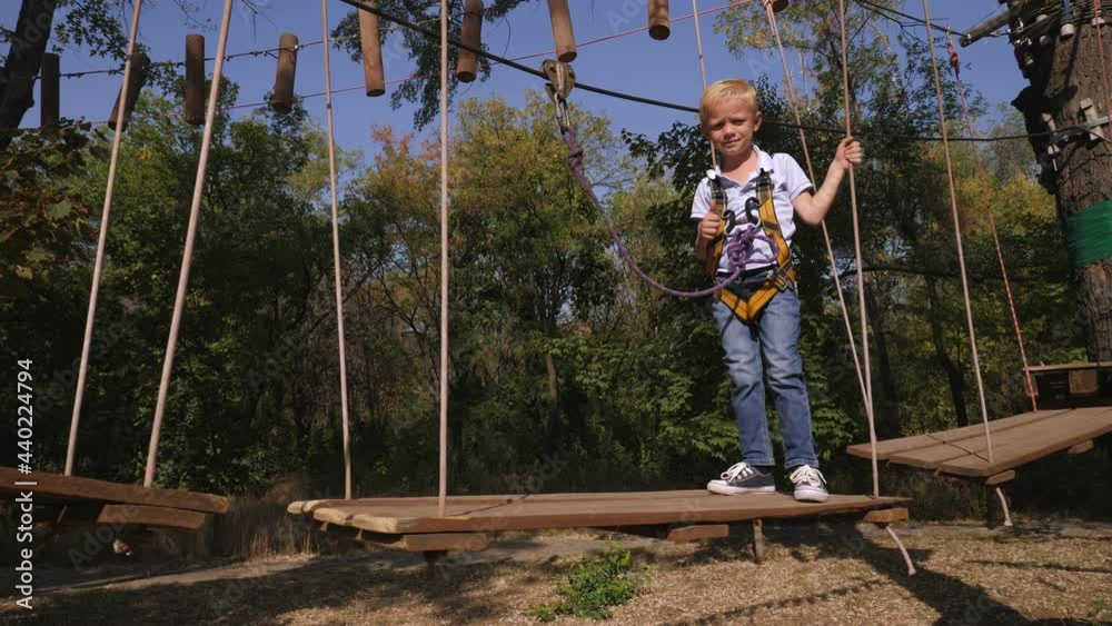 Cute boy in an adventure park are engaged in rock climbing on the rope road. Cute boy in an adventure park are engaged in rock climbing on the rope road.