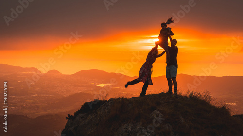 Silhouettes of parents playing with their son in a beautiful sunset on the mountain. Adventure lifestyle A summer afternoon in the mountains of the Basque country