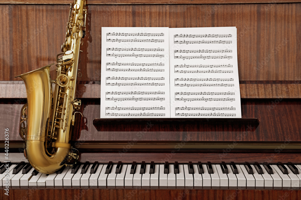 Naklejka premium Beautiful saxophone on piano keys. Musical instruments