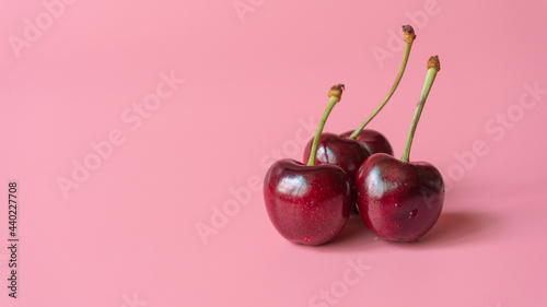 three heart shaped cherry berries isolated on pink background cutout
