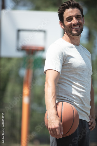handsome smiling man carrying a basketball ball