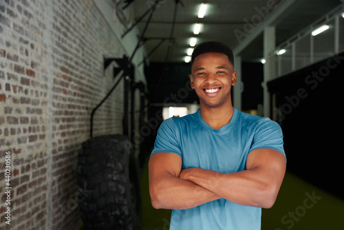 African American male standing with crossed arms in the gym. Male personal trainer looking intensely at the camera. High quality photo