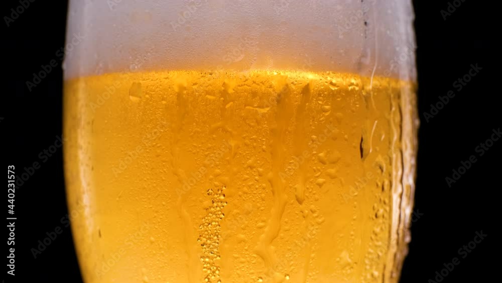 Beer glass with falling water drops. Refreshing and cold beer in a beer glass with water droplets. Cold light beer in a beer mug on a black background with water droplets and foam. Beer glass with falling water drops. Refreshing and cold beer in a beer glass with water droplets. Cold light beer in a beer mug on a black background with water droplets and foam.