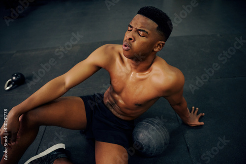 African American male resting on the gym floor after an intense cross fit session. Male athlete looking exhausted after the workout. High quality photo