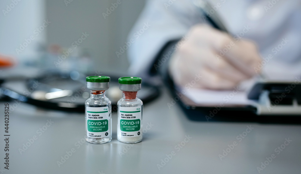 Two vials of coronavirus vaccine on a female doctor's table