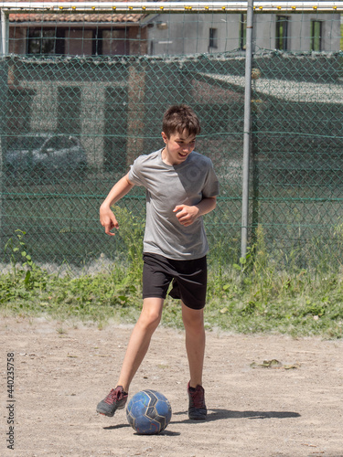 Teenage Boy Playing Soccer in a Dusty Field