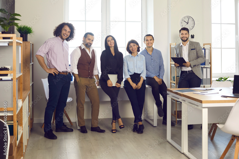 Group portrait of successful business people or company coworkers. Creative professional business team standing by window in modern office workplace. Concept of success and teamwork