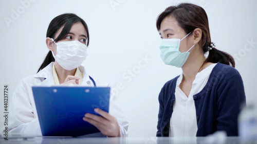 Doctor wearing protective mask consulting patient show X-ray result with digital tablet.