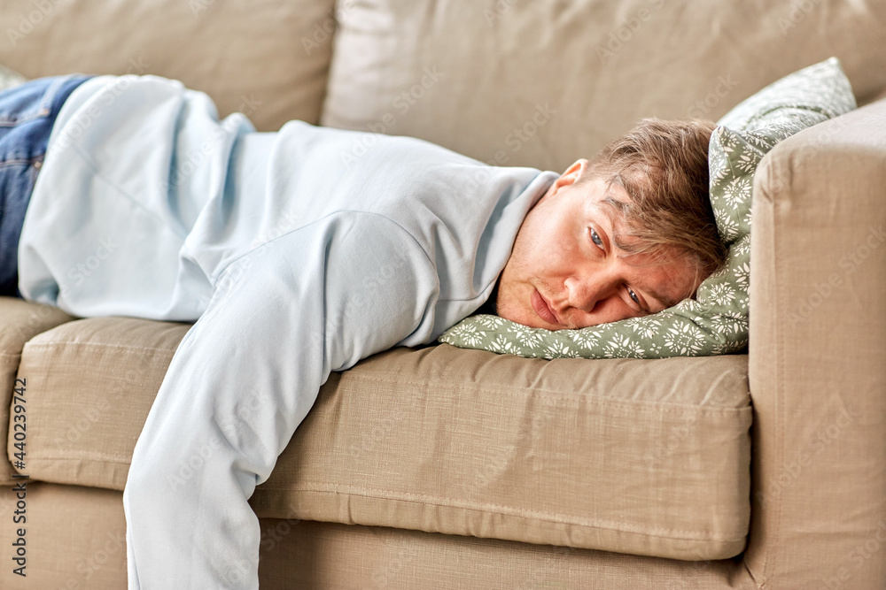 people, boredom and depression concept - bored or lazy young man lying on sofa at home people, boredom and depression concept - bored or lazy young man lying on sofa at home