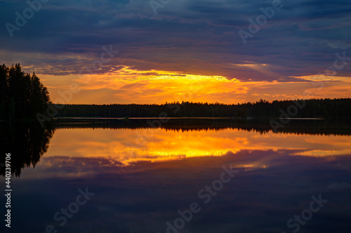 Scenic and beautiful sunset and colorful cloudy sky and their reflections on a lake in Finland at summer.