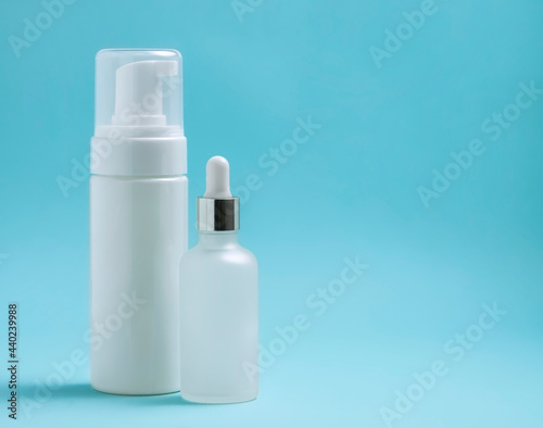 tube of mousse and a bottle of serum, foam container on blue background