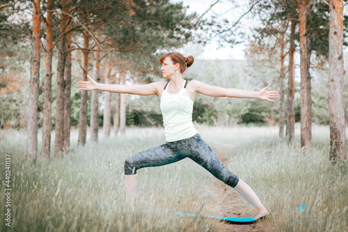 Sporty woman practicing yoga, stretching and relaxation in park outdoors, fitness in nature