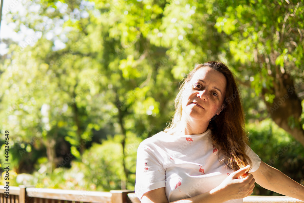 Retrato de una mujer joven bonita tacandose el pelo en un parque Retrato de una mujer joven bonita tacandose el pelo en un parque