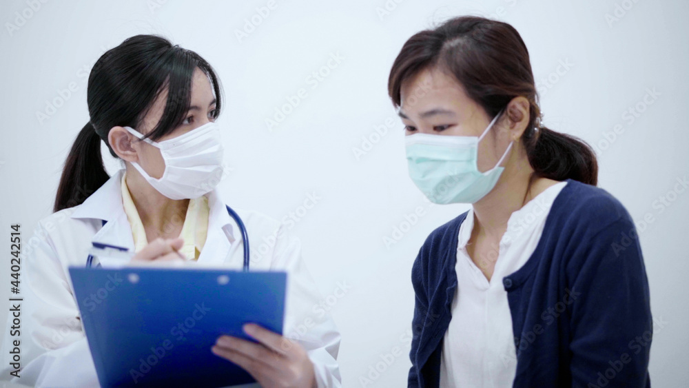 Doctor wearing protective mask consulting patient show X-ray result with digital tablet.