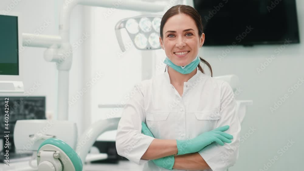 A pleased dentist woman is looking to the camera standing in the clinic