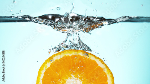 Fototapeta Naklejka Na Ścianę i Meble -  Fresh orange slice dropped into water with splash