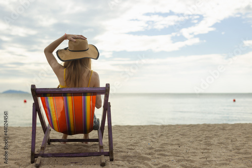 person wearing hat sitting on the beach chair