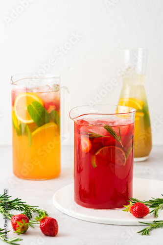 Jugs of fresh refreshing fruit drinks with fruit wedges, summer cold juices with ice © pundapanda
