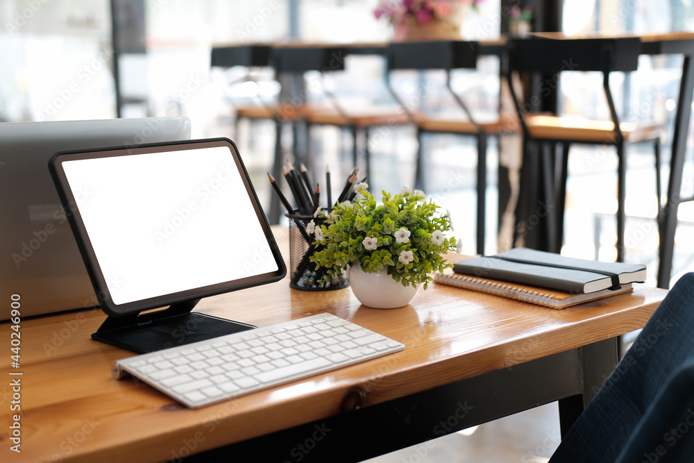 Front view of office desk with blank screen display of tablet in the cafe. Front view of office desk with blank screen display of tablet in the cafe.