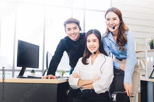 Team of happy Asian customer service looking at the camera in call center. Group of young smiling operator with headset in modern office.