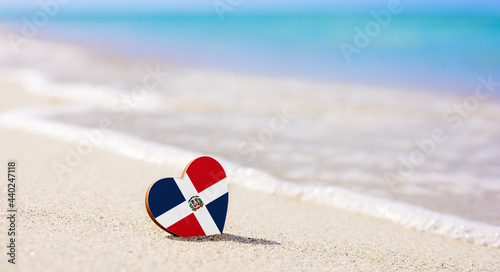Flag of the Dominican Republic in the shape of a heart on a sandy beach. The concept of the best vacation in Dominican Republic photo