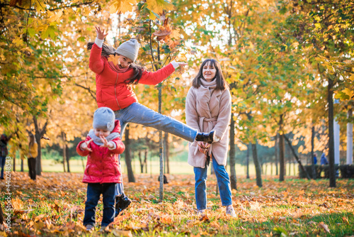 Mother and daughter having fun in the autumn park among the falling leaves. Active lifestyle