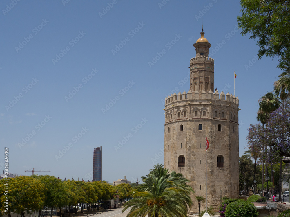 View of the Torre Sevilla (the city's first skyscraper) and the Torre del Oro (Tower of Gold) with palm tree and blue sky