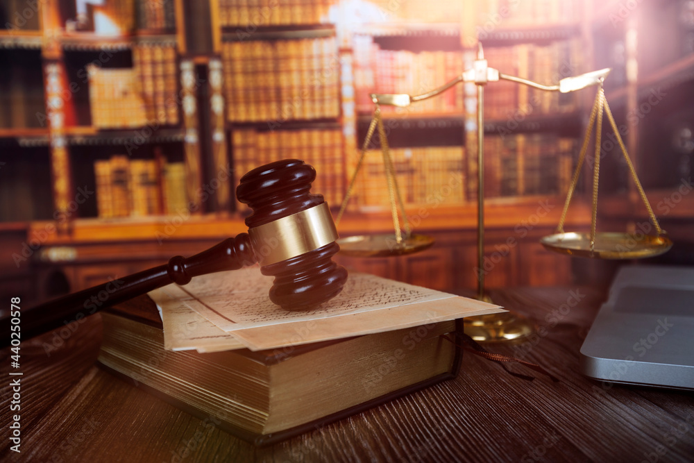 Justice and law concept.Male judge in a courtroom with the gavel, working with, computer and docking keyboard, eyeglasses, on table in morning light Justice and law concept.Male judge in a courtroom with the gavel, working with, computer and docking keyboard, eyeglasses, on table in morning light