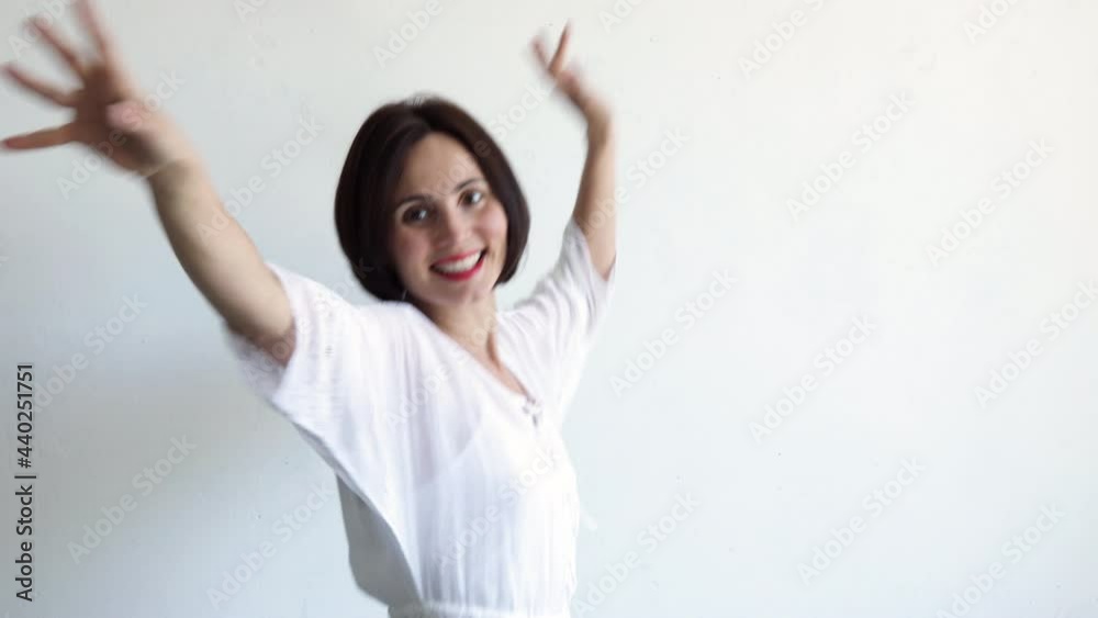 Beautiful happy smiling ethnical young woman pretty face dancing and laughing at home on the white background, girl in white dress with red lipstick and facial wrinkles. Copy space Beautiful happy smiling ethnical young woman pretty face dancing and laughing at home on the white background, girl in white dress with red lipstick and facial wrinkles. Copy space