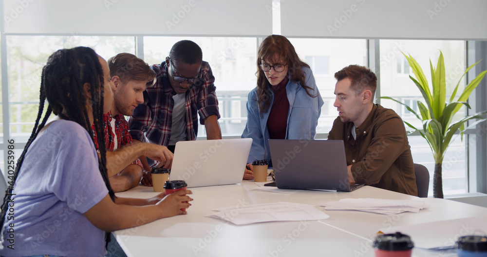 Group of young colleagues using laptop at office meeting