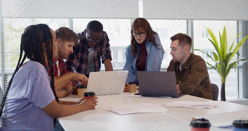 Group of young colleagues using laptop at office meeting