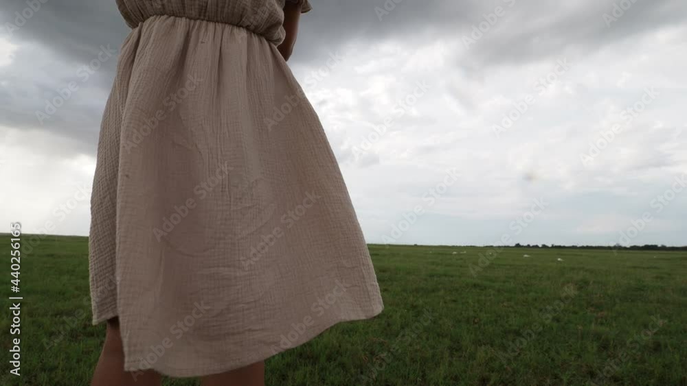 Woman in dress standing on field while wind is blowing her dress - freedom, nature concept 4k footage