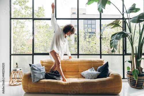 Принти на полотні Beautiful African american young woman dancing on couch, having fun, carefree in