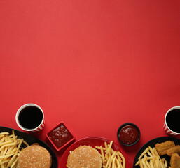Different fast food on red background, flat lay. Space for text