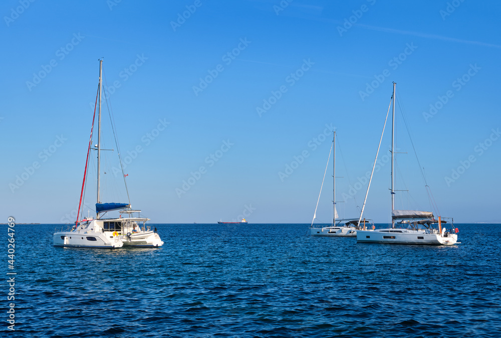Sailing yacht catamarans, Mediterranean sea, clear blue sky and sea waters. Summer entertainment, fun sailing, swimming, Greek islands, seascape.