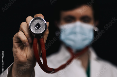 Médico con estetoscopio y la boca tapada por una mascarilla. photo