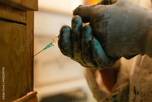 unrecognizable person applying product against woodworm with a syringe on wooden furniture. Restoration techniques.