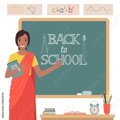 Indian woman teacher in front of a blackboard.