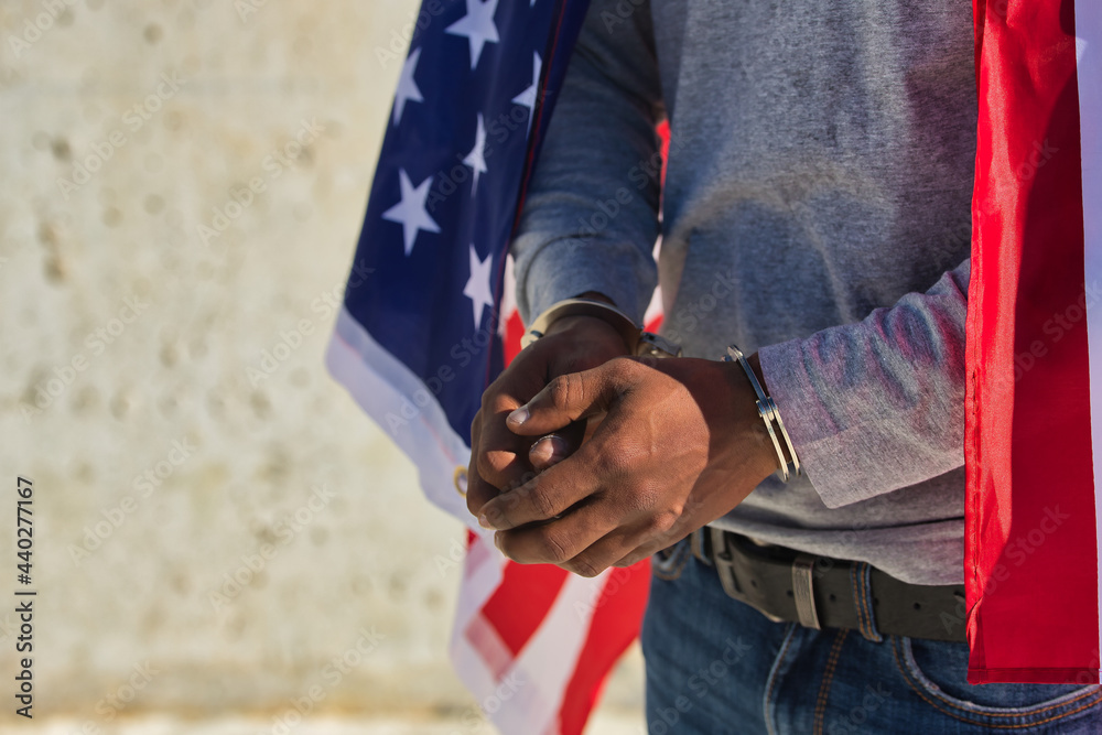 African american person with shackles in his hands and united states flag over his shoulders. Racial repression.