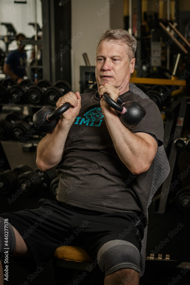 Concept of healthy lifestyle. Senior working out at the gym. Kettle bell workout. Concept of healthy lifestyle. Senior working out at the gym. Kettle bell workout.
