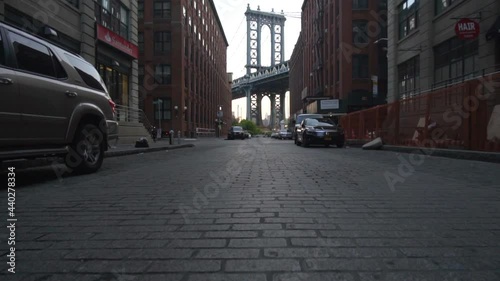 Brooklyn Bridge View from Dumbo with dumbo apartment houses and parked cars on the side in Summer in early morning light  photo