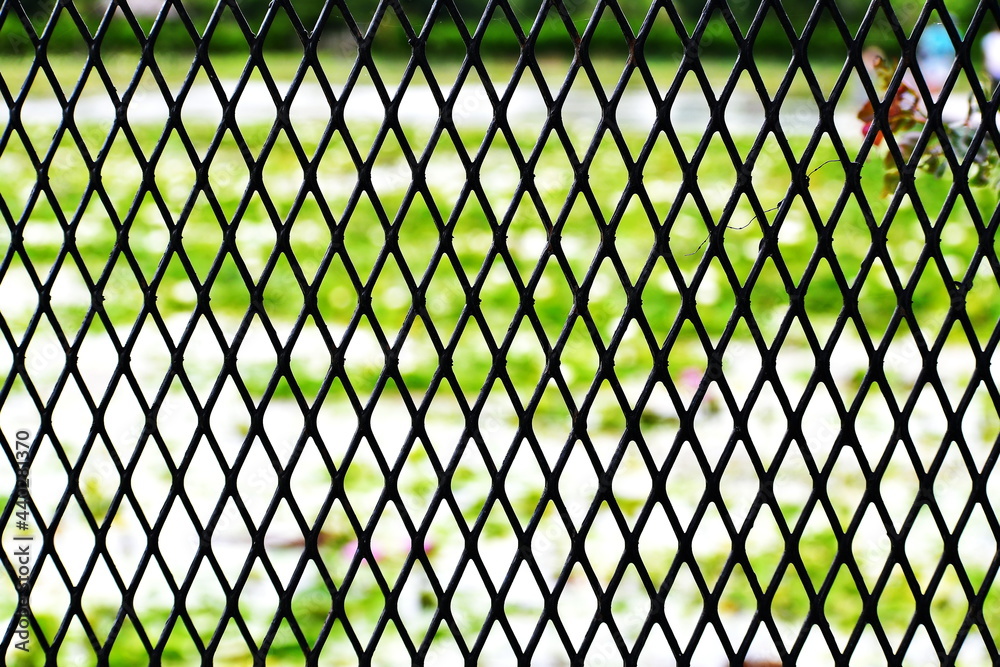 Fototapeta premium The surface of black plastic mesh and defocused nature background 