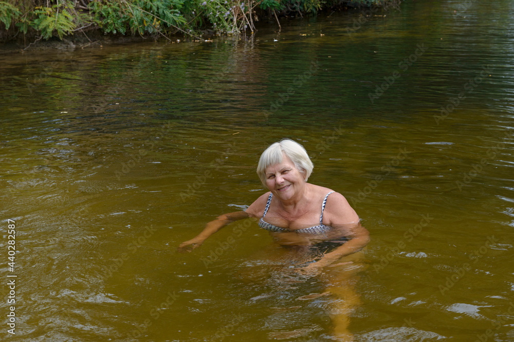 Fototapeta premium Woman is posing in the river water in cloudy day.