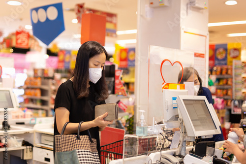 Woman with face mask checkout at counter cashier at grocery.
