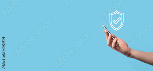 Male hand holding protect shield with a check mark icon on blue background. Protection network security computer and safe your data concept .