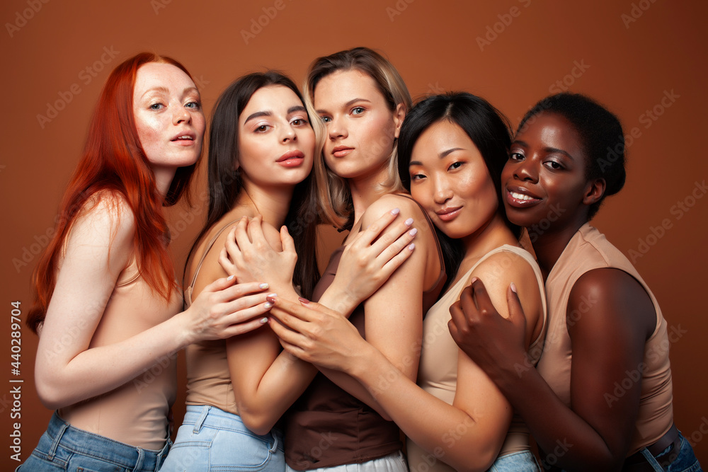 Obraz premium young pretty caucasian, afro, asian, scandinavian woman posing cheerful together on brown background, lifestyle diverse nationality people concept