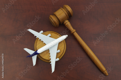 Flight cancellation, aviation law, sue airline company concept. Wooden judge gavel and airplane model on wooden background.